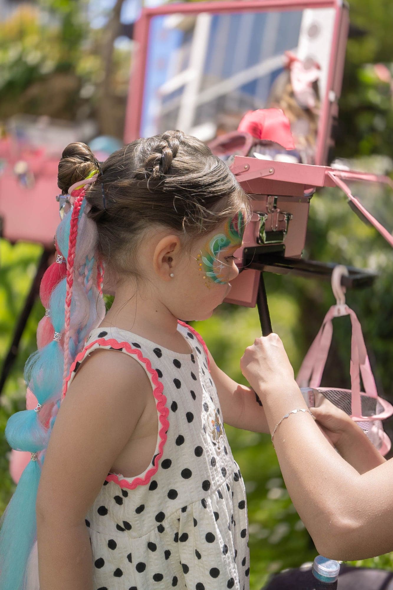 Niña con trenzas de colores frente a un espejo de maquillaje