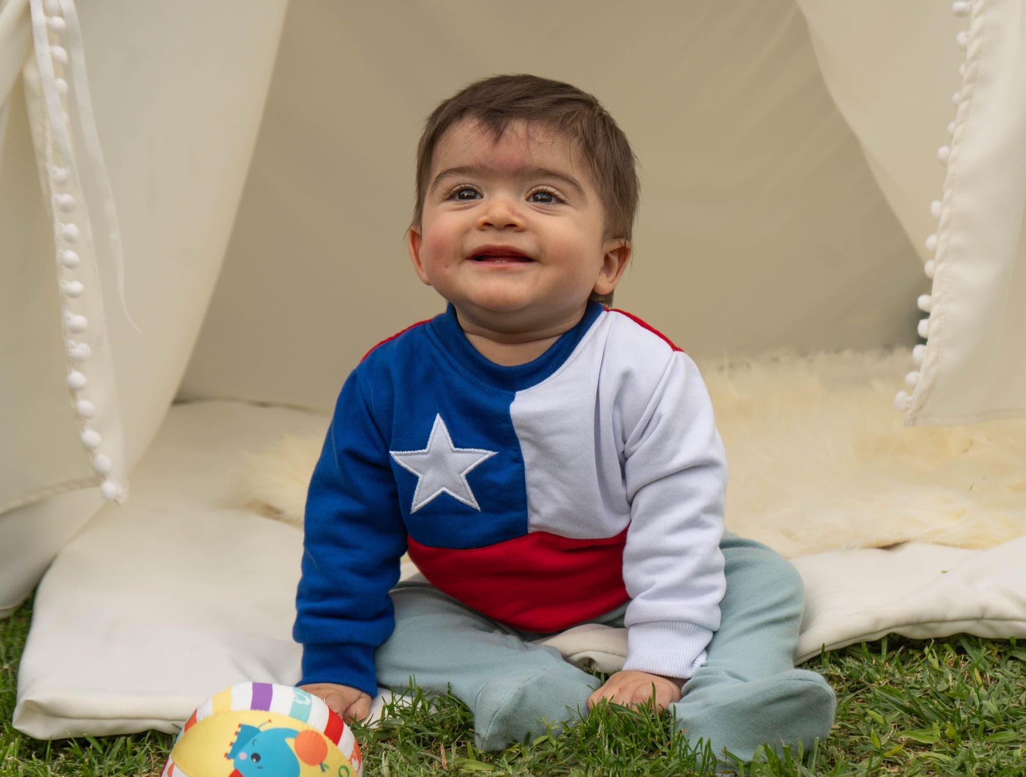 Rafita sonríe sentado frente a un tipi