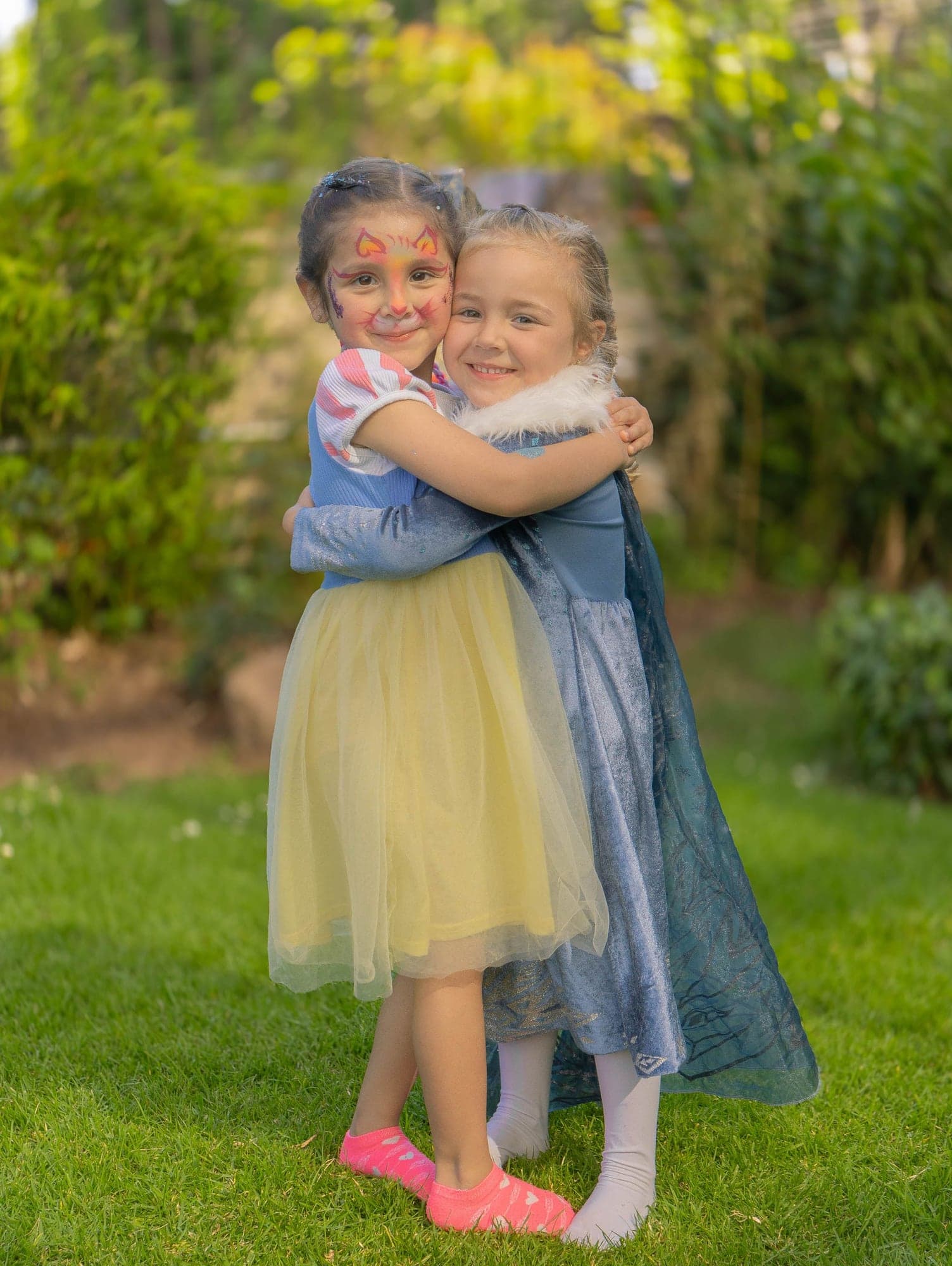 Dos amigas disfrazadas de princesas se abrazan en el jardín