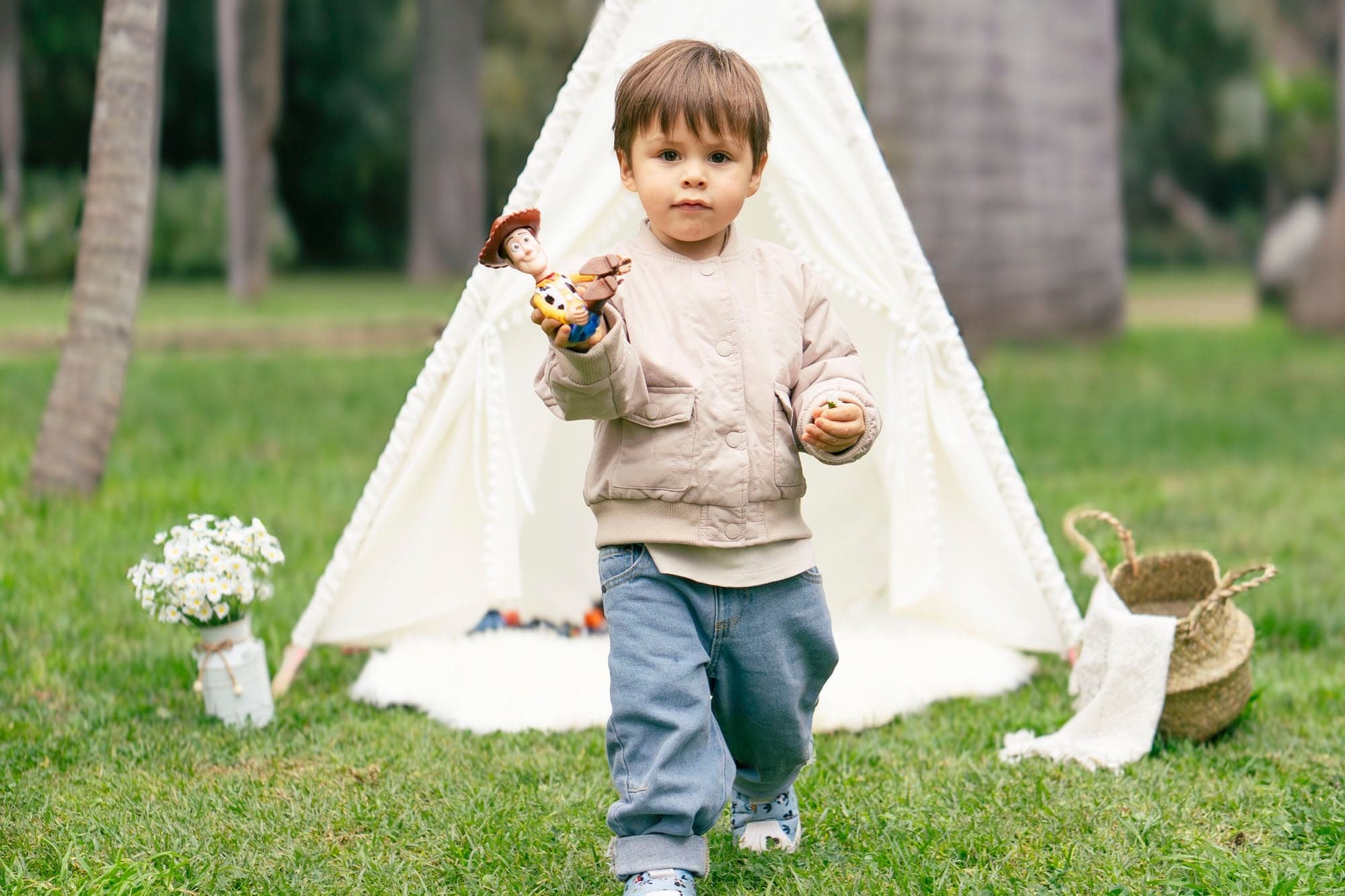 Niño camina con su juguete frente a un tipi en el parque